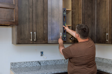 Level measurement tool is used by supervisor during assembly of new kitchen cabinets to ensure that installation is high qualityの写真素材