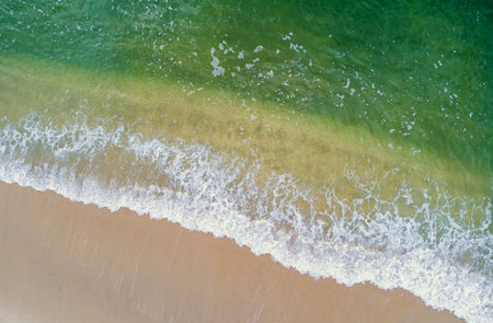 Surfing waves crashing against sandy shore crashing waves on sand beach in aerial view oceanの写真素材