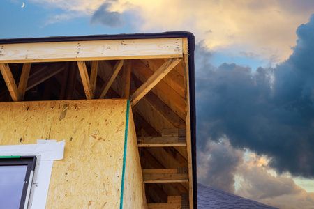 During construction of house, joist framework featuring plywood is installed, gutter holders are...