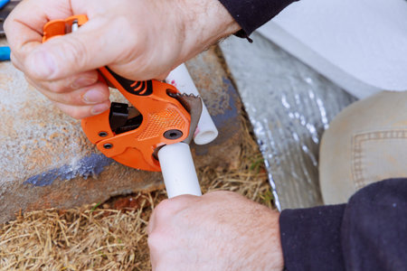 When installing water pipe, plumber cuts plastic PVC pipe with special scissorsの写真素材