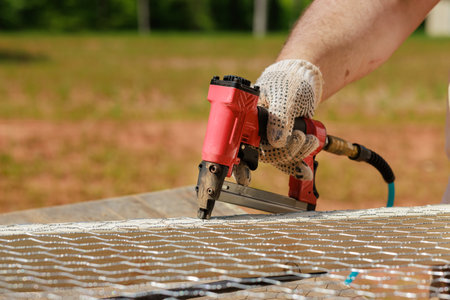 Farmer makes outdoor of chicken coop for chickens nailing metal meshの写真素材
