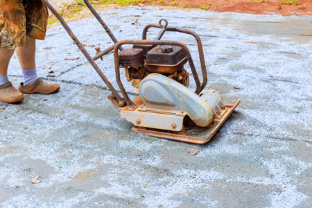 Vibratory tamping machine compacting sand during construction of pool platform