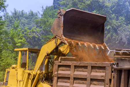 Bucket of bulldozer fills with earth in an industrial zone