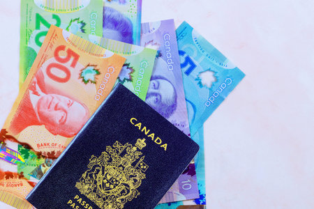 An official passport issued by Canadian government accompanied by Canadian banknotes in currency dollars in various denominationsの写真素材