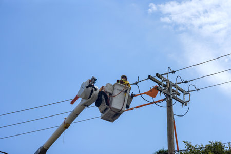Using insulated equipment, lineman electrician engineer work at pole to maintain service on power...