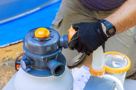 Swimming pool maintenance workers assemble sand filter system tank cleaning equipmentの写真素材