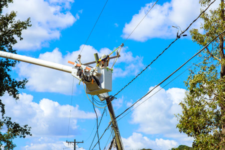Using utility tower truck, emergency service linemen repair power electrical lines damaged by storm...