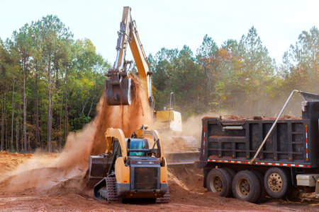 Loading land into dump truck using excavator at construction site