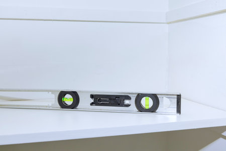 Construction level is placed on newly shelf, aiding in accurately checking horizontal alignment...