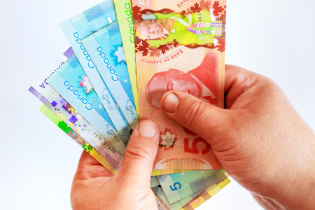 Hand holding counting Canadian money dollar cash banknotes bills in various denominationsの写真素材