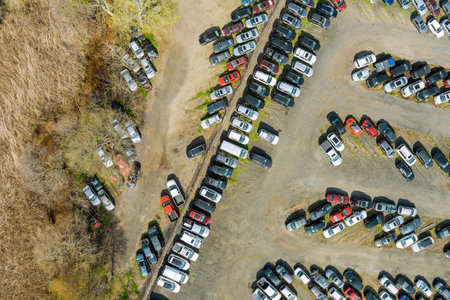 Vast parking lot is filled with many different vehicles organized in rows.の写真素材