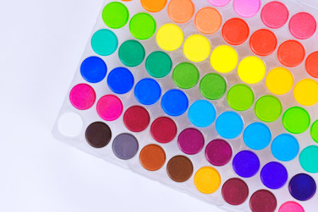 Artists hobbyists essential tools, colorful paints palette of watercolors arranged in rainbow of...
