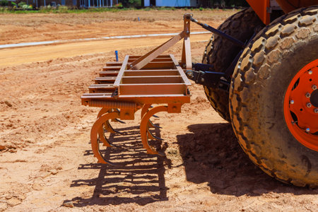 Tractor with tilling attachment is working on construction site, preparing dirt for future building...