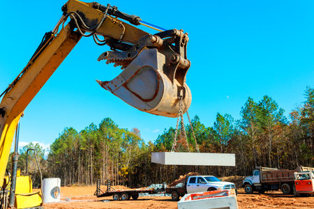 Large excavator lifts concrete block at construction site while during residential build works areaの写真素材