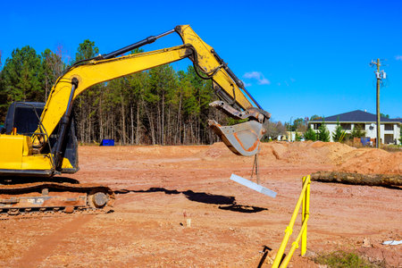 An excavator uses its arm to lift concrete slab at construction site during residential build works...
