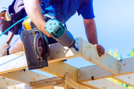 Carpenter working diligently on wooden framework, using air nail gun, power tool under construction...