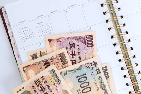 Japanese yen bills are arranged on an open calendar symbolizing budget planning savings, notebook gold spiral neat calendar layout organized feelの写真素材