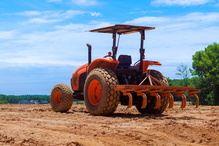 Tractor works diligently to till soil in an open field under sunshine, enhancing the landscape.