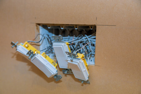Renovation reveals hanging electrical switches with complex wiring an unfinished patch on wall.
