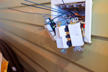 Technicians are installing multiple electrical light switch on wall in home, working carefully with...