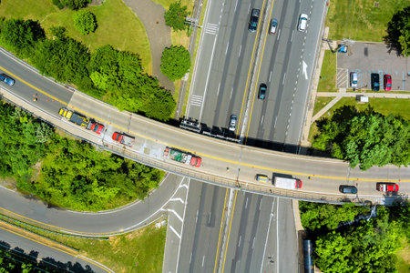 Vehicles navigate multi lane road with lush trees lining edges in bustling suburban American town at New Jerseyの写真素材
