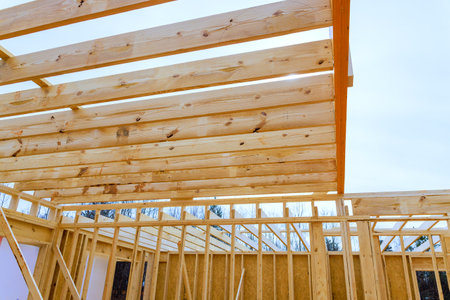 Workers are assembling wooden beams framework at construction site surrounded by roof timberの写真素材