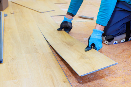 Worker installs planks of wooden flooring with care in residential space during room renovationの写真素材