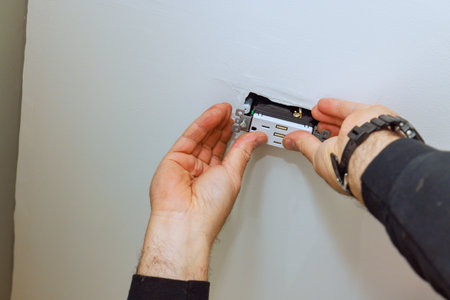 Electrician person is carefully placing an electrical outlet into ceiling of homeの写真素材