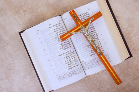 24 April 2025 Jerusalem Israel Cross rests on pages of an open Hebrew Holy Bible, emphasizing faith and spirituality in Messianic Jewish Congregation during prayer time "Hebrew Tanakh prayer holy book"の写真素材