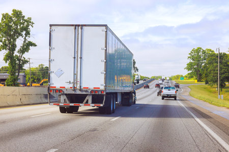 Large truck moves along multi lane American highway with vehicles in motion under clear sky.の写真素材