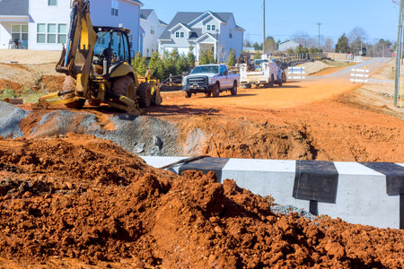 Heavy machinery operates on rural road, repairing surface while vehicles await passage at works zone progress.の写真素材