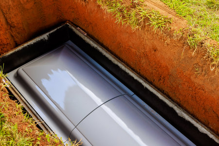 Gray coffin rests in grave before closing at cemetery surrounded by earth somber atmosphere evokes...
