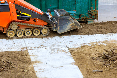 Heavy machinery is preparing ground with precision for new sidewalk installation near large...