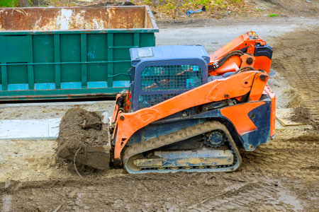 Construction equipment clears dirt soil while preparing site for new building woks