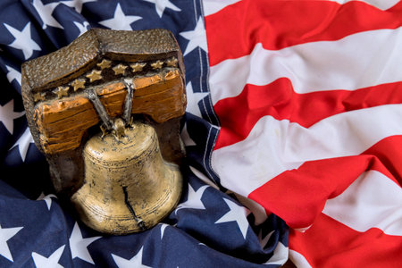Ornate bell remembrance symbol is placed on folded American flag, highlighting themes of freedom national identity.の写真素材