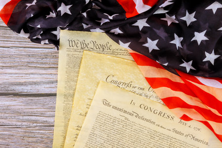 Founding of Independence US documents are laid out on waving American flag, symbolizing national...