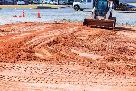 Heavy machinery levels red clay surface in construction site on foundation zone areaの写真素材