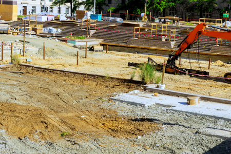 Heavy machinery is actively working on construction site where groundwork is being prepared for...