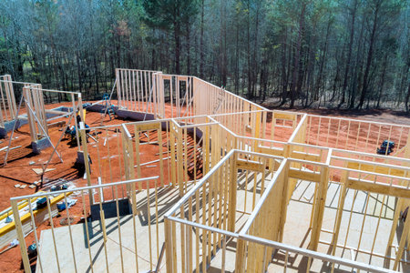 Workers are constructing beams frame of new house surrounded by trees on suburban location landscape