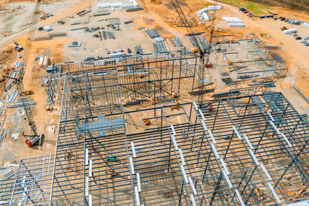 Workers are assembling large steel framework at busy construction site surrounded by materials.の写真素材