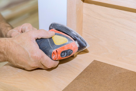 Skilled craftsman uses power sander on wooden surface to achieve smooth finish at wooden railings, stairsの写真素材