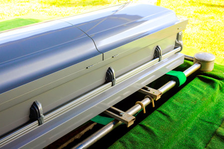 Casket placed on green surface, prepared for burial while surrounded by serene cemetery atmosphereの写真素材
