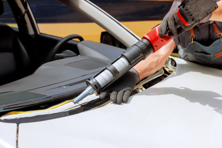 Skilled technician works on removing windshield with specialized tools in auto repair environment.の写真素材