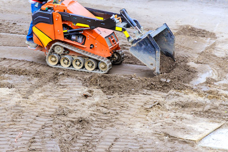 Compact track loader is used to move level soil at construction site during works dayの写真素材