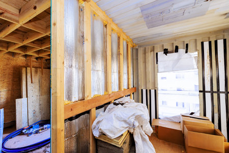 Workers are renovating an interior area, exposed insulation construction materials during daytime...
