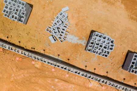 Aerial view of construction site featuring stacks of concrete blocks on dusty terrain under work day