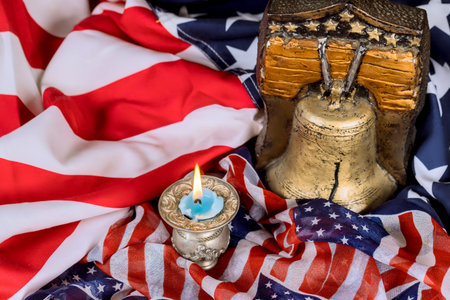 USA bell, candle rest on an American flag, symbolizing liberty remembrance symbol of freedom in reflective moment.の写真素材