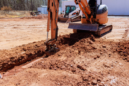 Heavy machinery is digs trench as workers prepare for construction location.