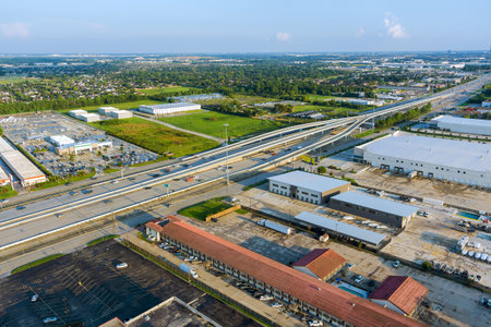 Complex multi level highway intersection with industrial warehouses, parking lots, surrounding...