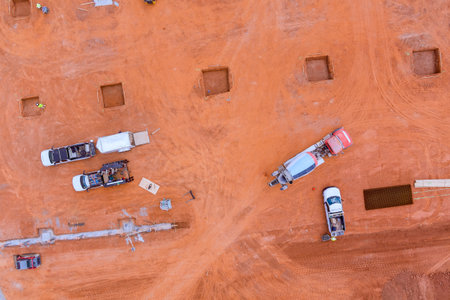 Workers operate machinery prepare the site for building foundations in an expansive, open area.の写真素材